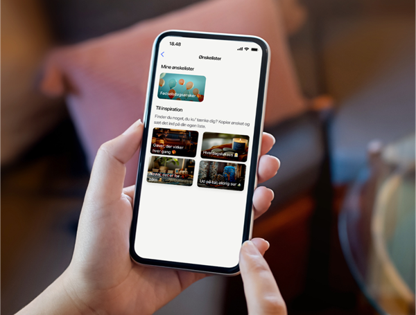 En hånd med en telefon, som viser inspirationsønskelister i MobilePay