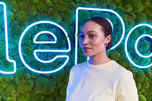 Portrait of a girl standing in front of a green MobilePay wall.