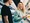 Man and woman in the railway station talking. Woman is holding a mobile phone.