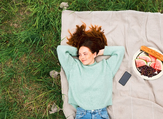 Girl in a park relaxing on a blanket.
