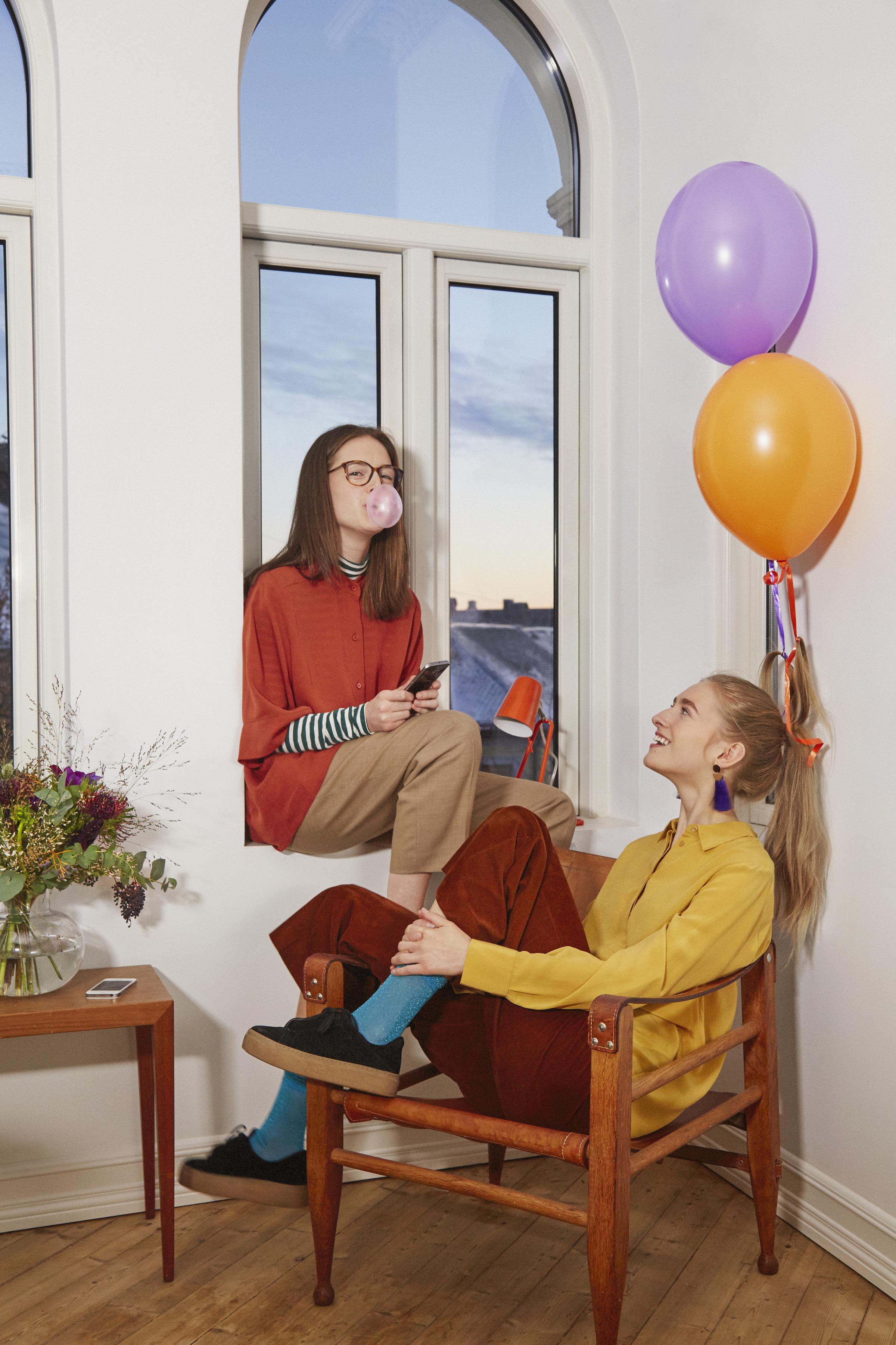 Image of two girls chatting in a window.