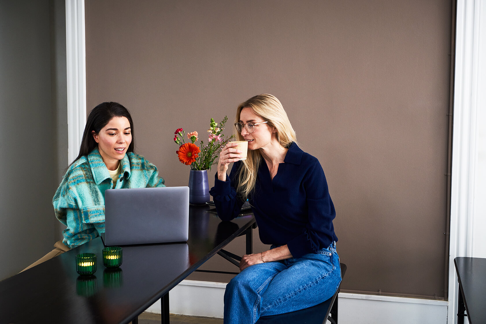Two women having coffee and working on a computer together