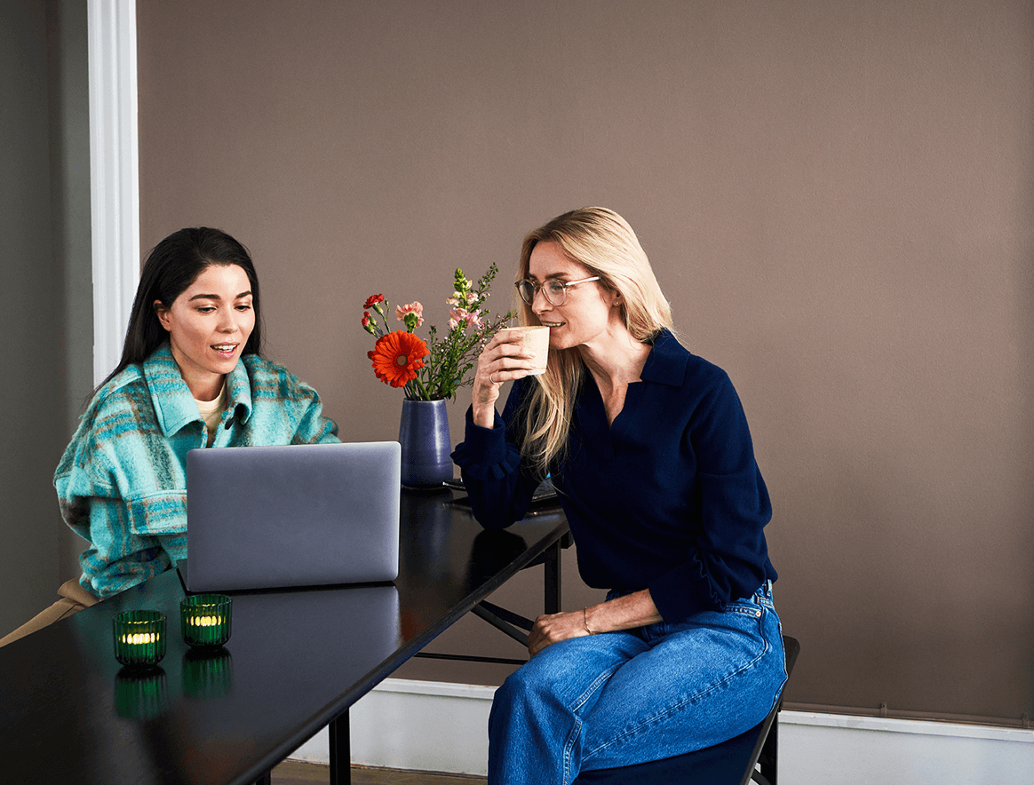 Two women having coffee and working on a computer together